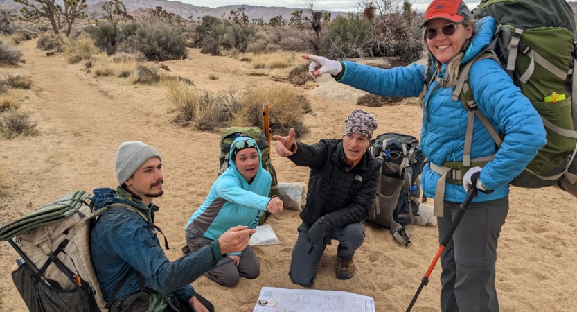 A group of people gathered around a map point in different directions in a joking manner